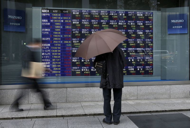 &copy; Reuters. FILE PHOTO: A man holding an umbrella looks at an electronic stock quotation board outside a brokerage in Tokyo April 7, 2015.  REUTERS/Issei Kato