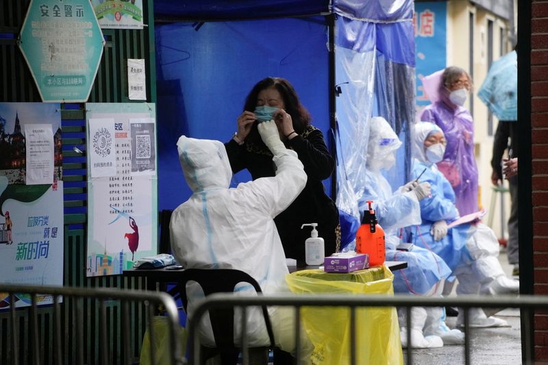 &copy; Reuters. A medical worker in a protective suit collects a swab sample from a resident for nucleic acid testing,  during lockdown amid the coronavirus disease (COVID-19) pandemic, in Shanghai, China, May 13, 2022. REUTERS/Aly Song