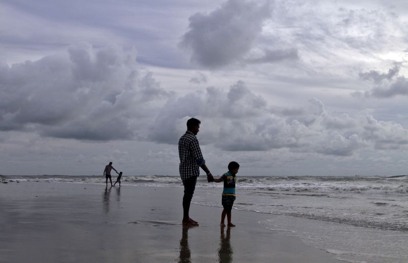 &copy; Reuters. Pai e filho em uma praia com nuvens de pré-monção no fundo, em Kochi, Índia.
04/06/2015 
REUTERS/Sivaram V