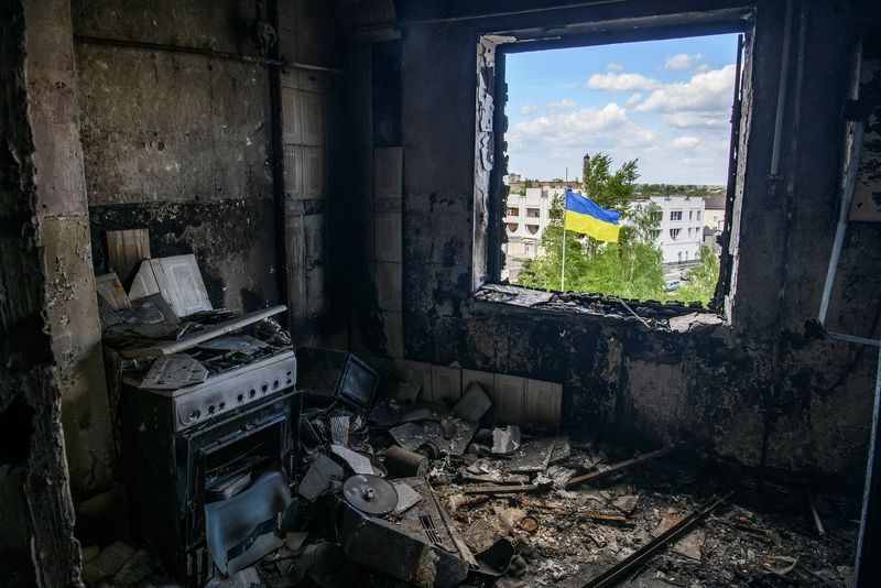 &copy; Reuters. Ukrainian national flag is seen through the window of an apartment destroyed during Russia's invasion of Ukraine in the town of Borodianka, in Kyiv region, Ukraine May 13, 2022.  REUTERS/Vladyslav Musiienko