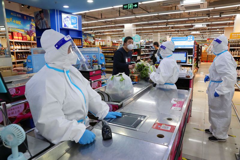 © Reuters. FILE PHOTO: Workers in protective suits attend to a customer at a checkout counter of a reopened supermarket, amid the coronavirus disease (COVID-19) outbreak, in Shanghai, China May 5, 2022. Picture taken May 5, 2022. China Daily via REUTERS