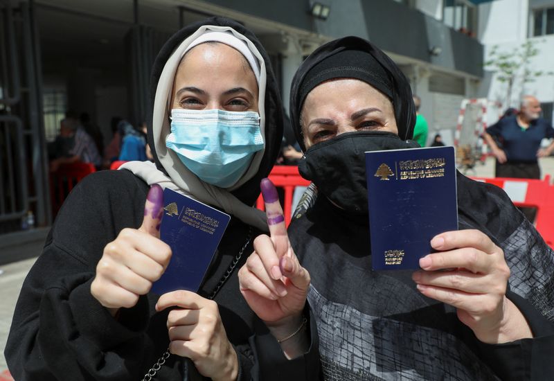 © Reuters. Women pose as they hold their Lebanese passports and show their ink-stained fingers after casting their vote in Lebanon's parliamentary election, in Beirut, Lebanon May 15, 2022. REUTERS/Mohamed Azakir