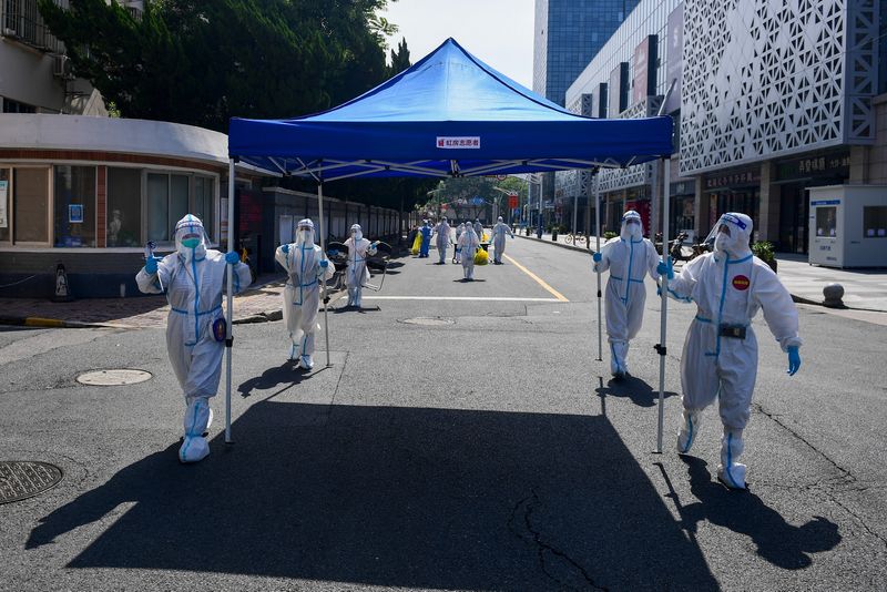 &copy; Reuters. Workers in protective suits move equipment for a makeshift nucleic acid testing site to the next residential area after wrapping up the screening at a compound, amid the coronavirus disease (COVID-19) outbreak in Shanghai, China May 14, 2022. Picture take