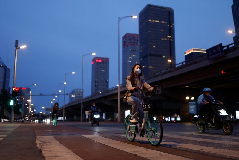 &copy; Reuters. امرأة تضع كمامة تقود دراجة هوائية في شارع ببكين يوم 12 مايو أيار 2022. تصوير: كارلوس جارسيا راولينز - رويترز