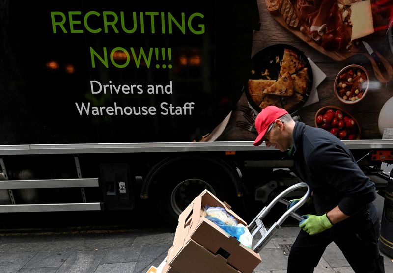 &copy; Reuters. FILE PHOTO: A lorry driver passes a sign on the side of his vehicle advertising for jobs as he makes a delivery, in London, Britain, October 13, 2021. REUTERS/Toby Melville