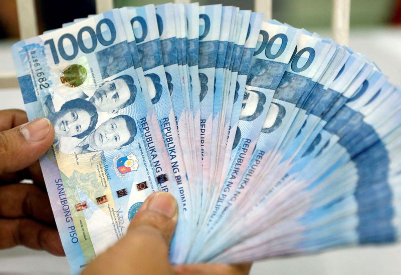 &copy; Reuters. FILE PHOTO: A worker shows Philippine peso bills inside a money changer in metro Manila, Philippines August 14, 2017. REUTERS/Dondi Tawatao