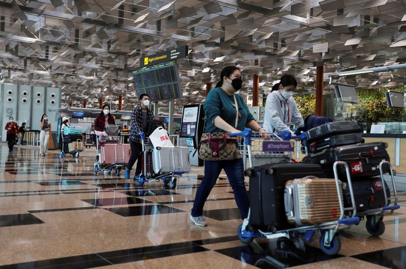 &copy; Reuters. FILE PHOTO: Travellers walk with their luggage at the Changi Airport in Singapore March 30, 2022. REUTERS/Edgar Su/Files