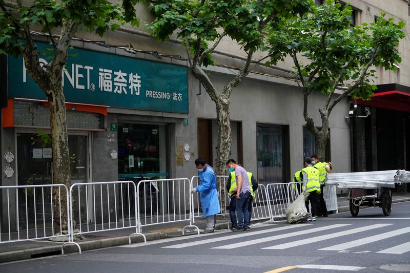 &copy; Reuters. عمال يقيمون حواجز لفصل إحدى المناطق خلال الإغلاق وسط جائحة فيروس كوفيد-19 في شنغهاي بالصين يوم الاثنين. تصوير: آلي سونج - رويترز