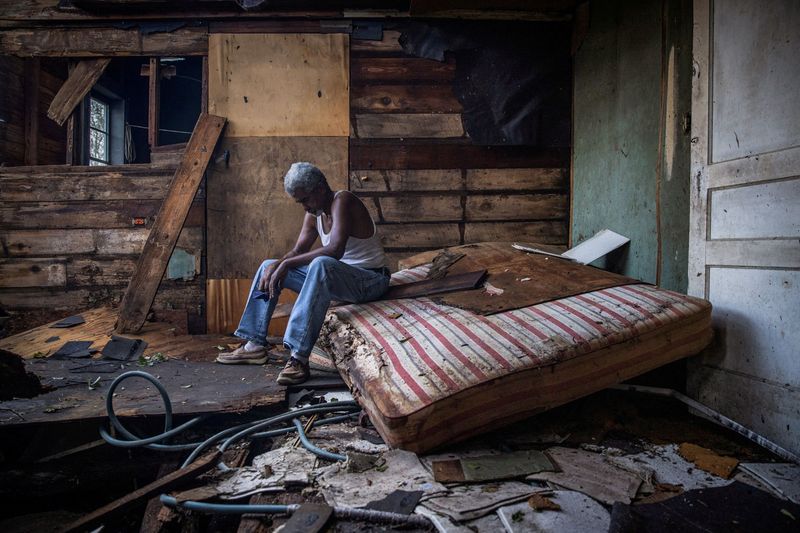 &copy; Reuters. FILE PHOTO: Theophilus Charles, 70, sits inside his house which was heavily damaged by Hurricane Ida in Houma, Louisiana, U.S., August 30, 2021. REUTERS/Adrees Latif   