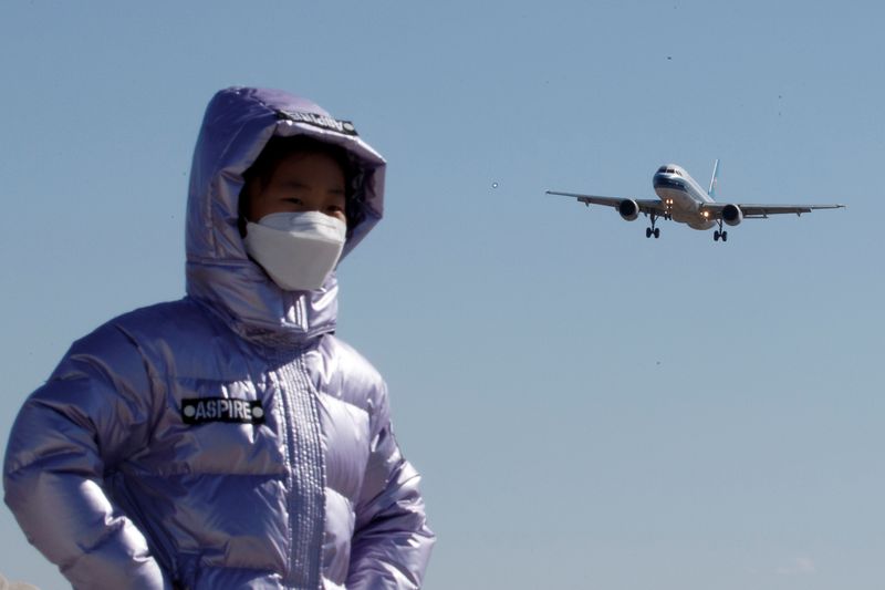 &copy; Reuters. FILE PHOTO: A child wearing a protective mask has her picture taken as a plane of China Southern Airlines lands at Beijing Capital International in Beijing as the country is hit by an outbreak of the novel coronavirus, China, March 13, 2020. REUTERS/Thoma