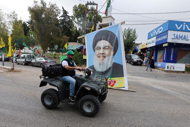 &copy; Reuters. Apoiador do movimento xiita Amal passa em frente a pôster com imagem do líder do Hezbollah Hassan Nasrallah em Houla, no sul do Líbano
15/05/2022 REUTERS/Aziz Taher