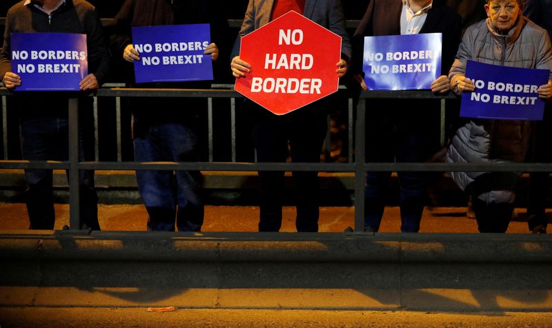 &copy; Reuters. FILE PHOTO: People hold placards as they attend a candlelit vigil on the border between Ireland's Donegal county and Londonderry county in Northern Ireland in Lifford, Ireland, October 16, 2019. REUTERS/Phil Noble/File Photo