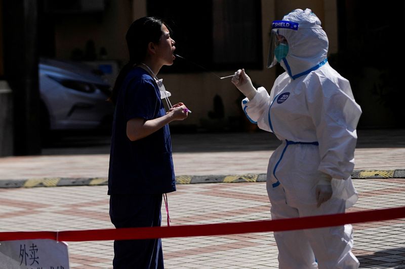 © Reuters. A medical worker collects a swab sample from a woman at a nucleic acid testing site on a street during lockdown, amid the coronavirus disease (COVID-19) pandemic, in Shanghai, China, May 18, 2022. REUTERS/Aly Song