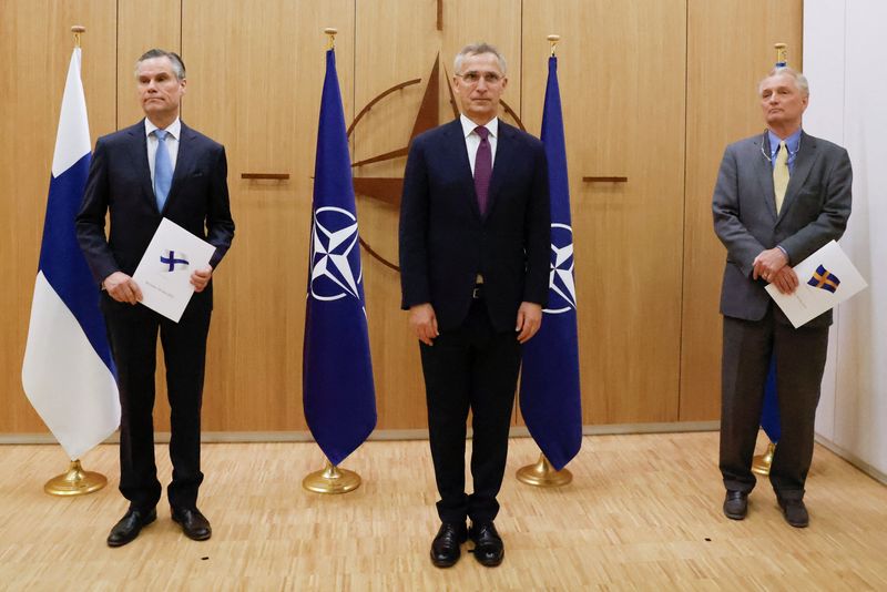 &copy; Reuters. Los embajadores de Finlandia (izquierda) y Suecia (derecha) ante la OTAN flanquean al secretario general de la OTAN, Jens Stoltenberg, mientras sostienen sendas carpetas con sus respectivas banderas nacionales en la ceremonia de entrega de la solicitud de