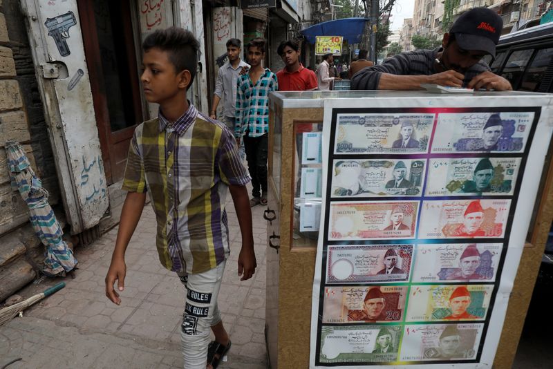&copy; Reuters. FILE PHOTO: A boy walks past a sidewalk money exchange stall decorated with pictures of banknotes in Karachi, Pakistan September 30, 2021. REUTERS/Akhtar Soomro