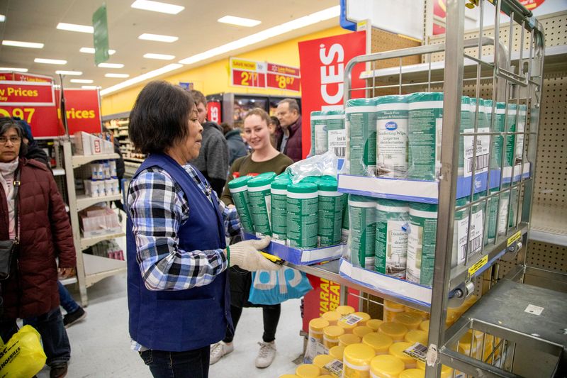 © Reuters. FILE PHOTO: People wait as an employee restocks a shelf with disinfectant wipes as people shop at a Walmart Supercentre amid coronavirus fears spreading in Toronto, Ontario, Canada March 13, 2020.  REUTERS/Carlos Osorio
