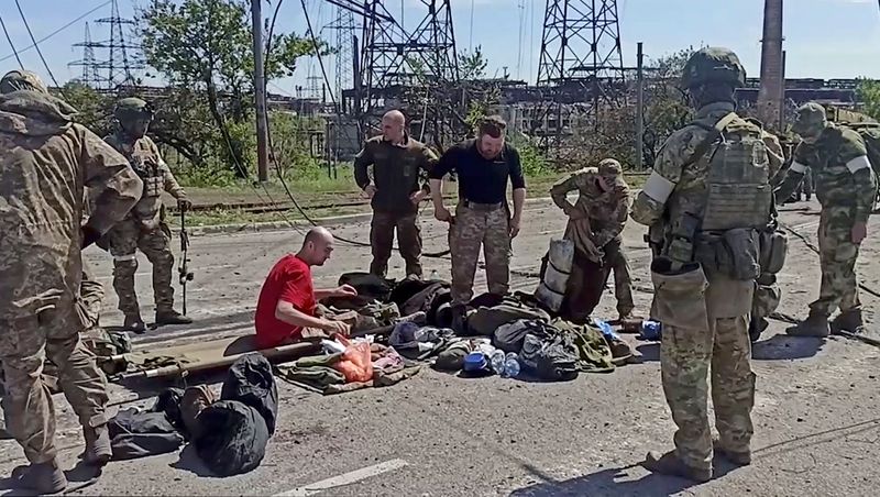 © Reuters. Service members of Ukrainian forces who have surrendered after weeks holed up at Azovstal steel works are being searched by the pro-Russian military in Mariupol, Ukraine, in this still image taken from a video released May 18, 2022. Russian Defence Ministry/Handout via REUTERS