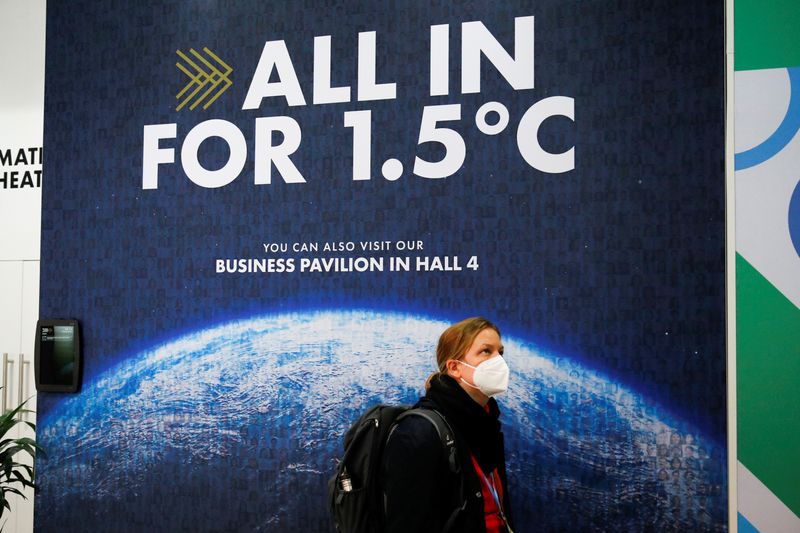 &copy; Reuters. FILE PHOTO: A delegate walks past a climate change poster at the UN Climate Change Conference (COP26) in Glasgow, Scotland, Britain, November 1, 2021. REUTERS/Phil Noble