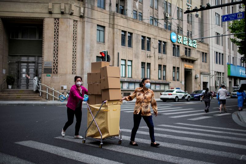 &copy; Reuters. امرأتان تحملان صناديق الطعام عبر شارع في شنغهاي في الصين حيث يفرض إغلاق بسبب تفشي فيروس كورونا يوم الأربعاء. تصوير: ألي سونغ - رويترز.