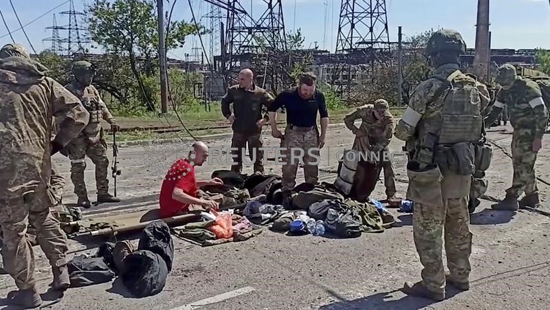 &copy; Reuters. Soldati ucraini arresisi dopo settimane all'interno dell'acciaieria Azovstal sono perquisiti dalla forze pro-russe a Mariupol. 18 maggio 2022. Russian Defence Ministry/Handout via REUTERS 