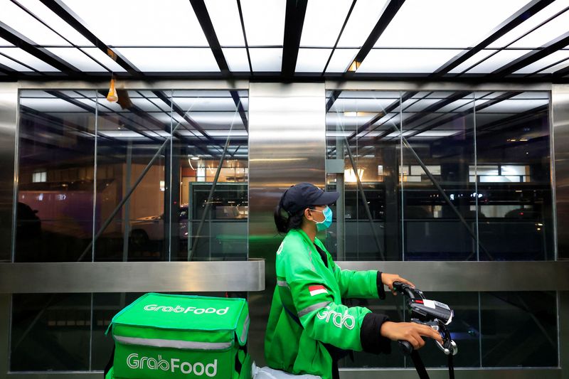 &copy; Reuters. FILE PHOTO: A driver working for the ridesharing company Grab holds a bicycle as she delivers food amid of the coronavirus disease (COVID-19) pandemic in Jakarta, Indonesia, March 15, 2022. REUTERS/Willy Kurniawan