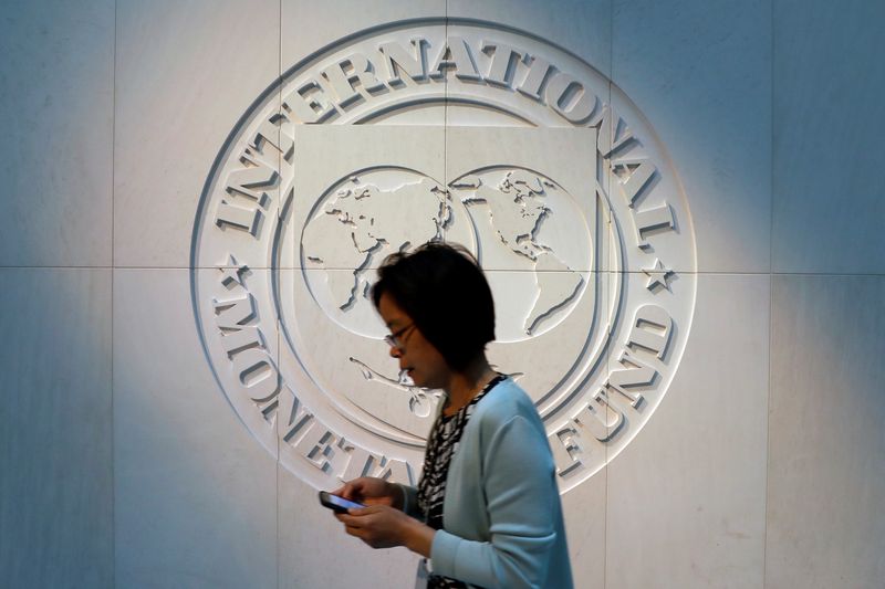 &copy; Reuters. FILE PHOTO: A woman walks past the International Monetary Fund (IMF) logo at its headquarters in Washington, U.S., May 10, 2018. REUTERS/Yuri Gripas