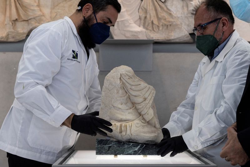 &copy; Reuters. FILE PHOTO: Two conservators hold a Parthenon fragment, on loan from the Antonino Salinas Regional Archaeological Museum of Palermo, at the Parthenon Gallery of the Acropolis Museum, in Athens, Greece, January 10, 2022. REUTERS/Alkis Konstantinidis