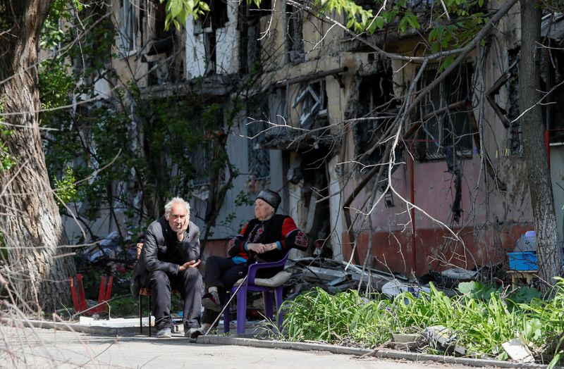 &copy; Reuters. FILE PHOTO: Local residents sit in a courtyard near a block of flats heavily damaged during the Ukraine-Russia conflict, in the southern port city of Mariupol, Ukraine May 20, 2022. REUTERS/Alexander Ermochenko 