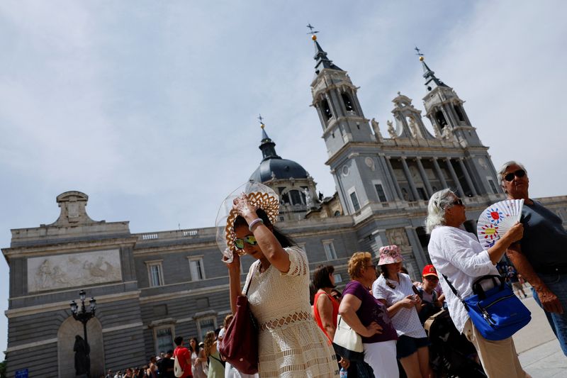 &copy; Reuters. Tourists use fans and hats for sun protection outside La Almudena Cathedral during an episode of exceptionally high temperatures for the time of year in Madrid, Spain, May 21, 2022. REUTERS/Susana Vera