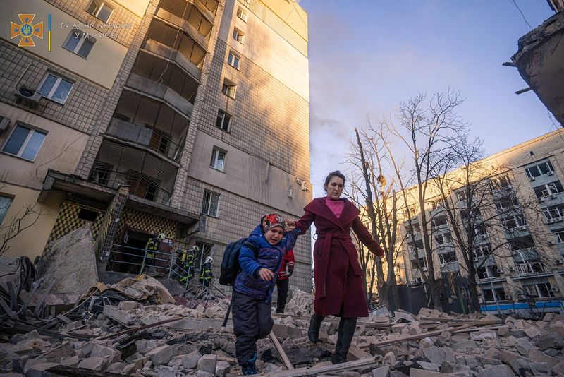 &copy; Reuters. FILE PHOTO: A woman with a child evacuates from a residential building damaged by shelling, as Russia's attack on Ukraine continues, in Kyiv, Ukraine, in this handout picture released March 16, 2022.  Press service of the State Emergency Service of Ukrain