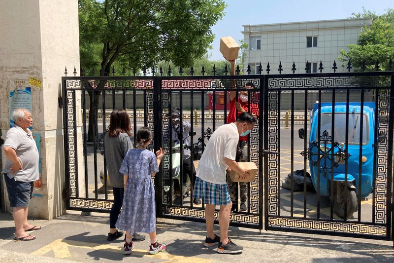 &copy; Reuters. A courier hands parcels through a closed gate of a residential compound where delivery workers are not allowed to enter, amid the coronavirus disease (COVID-19) outbreak, in Beijing, China May 22, 2022. Picture taken May 22, 2022. REUTERS/Martin Pollard