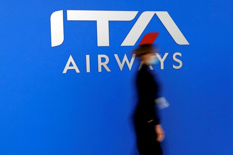 &copy; Reuters. FILE PHOTO: A woman walks past the logo of the new state-owned Italian carrier Italia Trasporto Aereo at Fiumicino airport before a news conference to present the aircraft's new fleet, in Rome, Italy, March 1, 2022. REUTERS/Remo Casilli