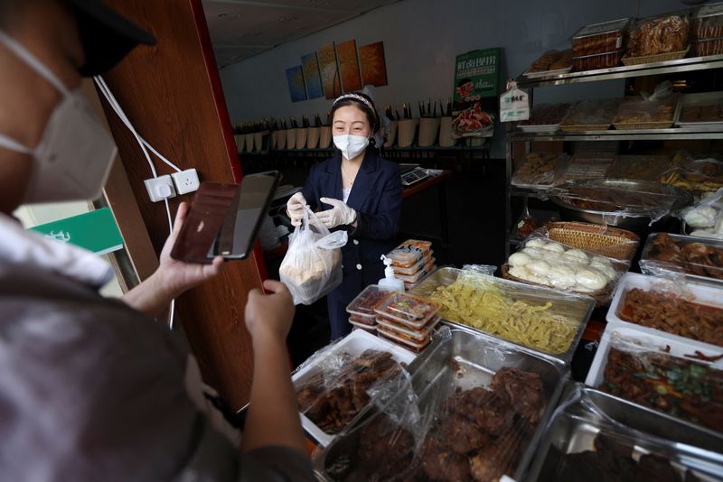 &copy; Reuters. FOTO DE ARCHIVO: Un miembro del personal sirve a un cliente durante las horas de almuerzo en un puesto instalado fuera de un restaurante, después de que la ciudad prohibiera los servicios de comedor durante el brote e COVID-19 en Pekín, China, 17 de may