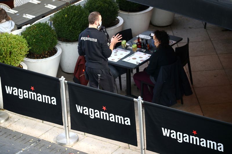 &copy; Reuters. FILE PHOTO: A waiter speaks with customers at a Wagamama restaurant in London, Britain, October 5, 2020. REUTERS/Hannah McKay