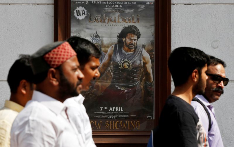© Reuters. FILE PHOTO: People walk past a poster of an Indian movie 