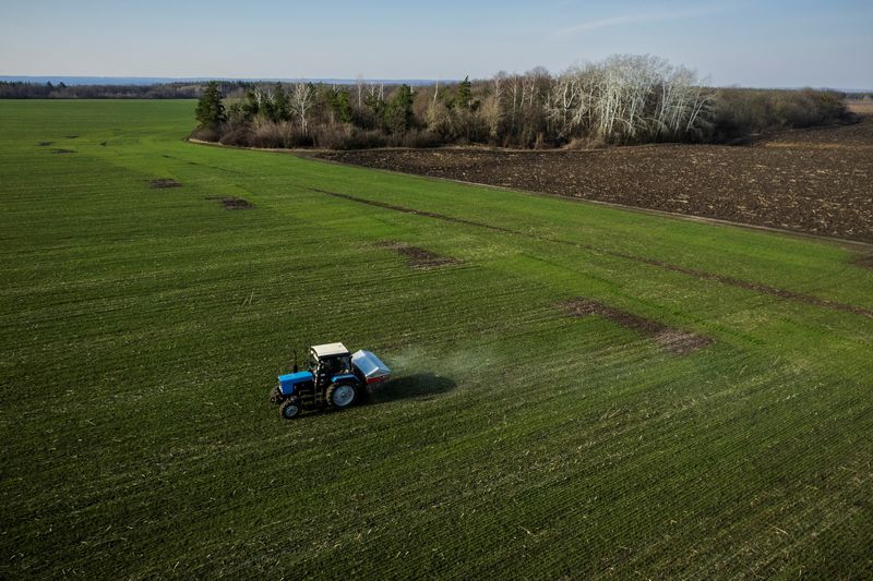 © Reuters. FILE PHOTO: An aerial view shows a tractor spreading fertiliser on a wheat field near the village of Yakovlivka after it was hit by an aerial bombardment outside Kharkiv, as Russia's attack on Ukraine continues, April 5, 2022. REUTERS/Thomas Peter
