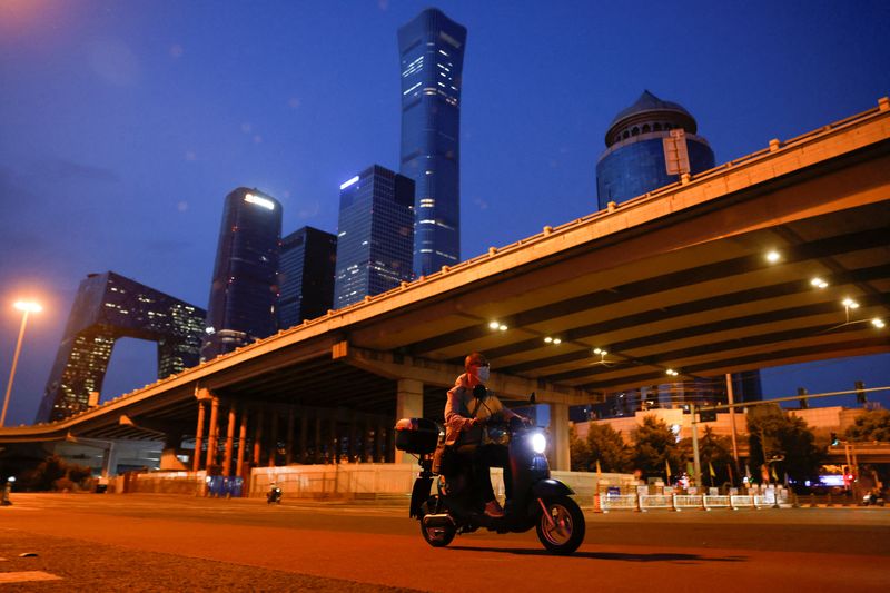 &copy; Reuters. Un hombre con una mascarilla en moto en la calle en el Distrito Central de Negocios (CBD), en medio del brote de la enfermedad del coronavirus (COVID-19) en Pekín, China 24 de mayo de 2022. REUTERS/Carlos García Rawlins