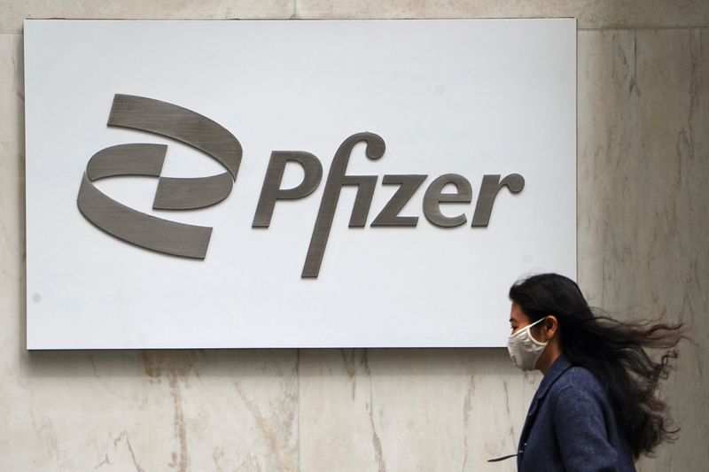 &copy; Reuters. FOTO DE ARCHIVO: Una mujer con mascarilla pasa frente al logotipo de Pfizer en la ciudad de Nueva York, Estados Unidos, el 1 de abril de 2021. REUTERS/Carlo Allegri