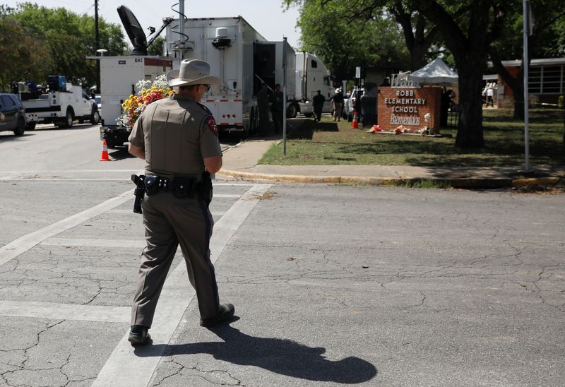 &copy; Reuters. A Texas Public Safety officer walks holding flowers at Robb Elementary school, the day after a gunman killed 19 children and two teachers at the school in Uvalde, Texas, U.S. May 25, 2022. REUTERS/Marco Bello