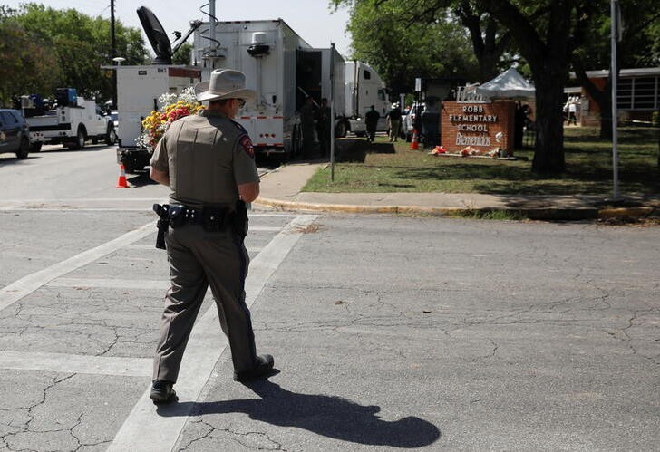 &copy; Reuters. Un oficial de seguridad pública de Texas camina con flores en la escuela primaria Robb, el día después de que un hombre armado matara a 19 niños y dos maestros en la escuela en Uvalde, Texas, EEUU. 25 de mayo de 2022. REUTERS/Marco Bello