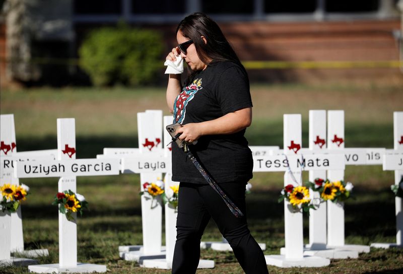 &copy; Reuters. A woman walks past crosses with the names of victims of a school shooting, at a memorial outside Robb Elementary school, after a gunman killed nineteen children and two teachers, in Uvalde, Texas, U.S. May 26, 2022. REUTERS/Marco Bello