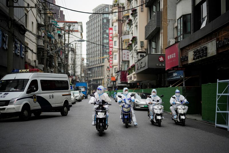 © Reuters. Worker in protective suits  ride electric scooters across the street at a closed residential area during lockdown, amid the coronavirus disease (COVID-19) outbreak, in Shanghai, China, May 26, 2022. REUTERS/Aly Song