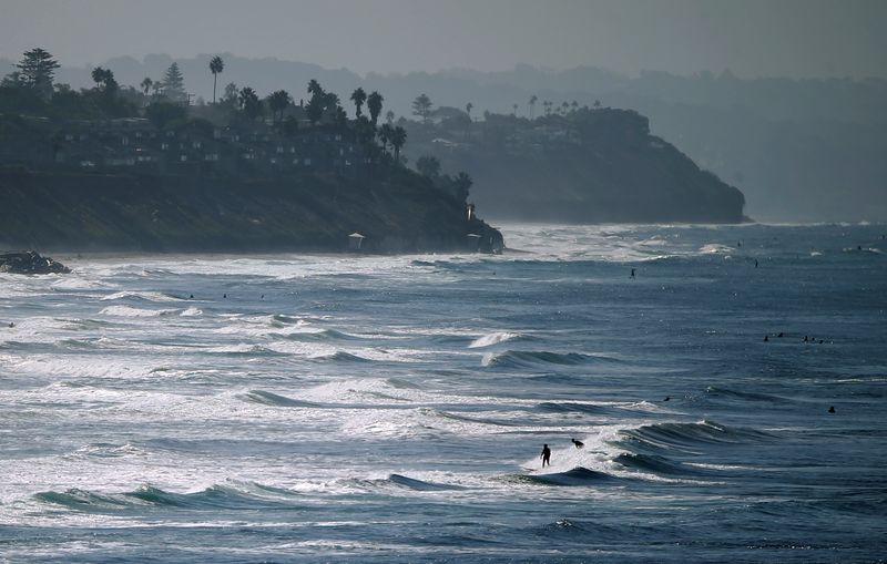 © Reuters. FILE PHOTO: People enjoy the beach and waves on an autumn day along the coast in Carlsbad, California,U.S., October 3, 2016.   REUTERS/Mike Blake 