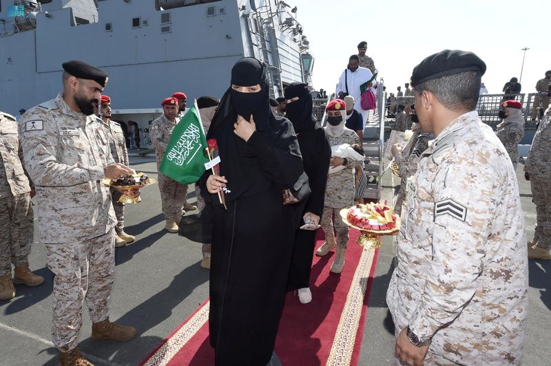 © Reuters. مسؤولون من القوات البحرية الملكية السعودية يرحبون بمواطنين سعوديين وأشخاص من جنسيات أخرى لدى وصولهم إلى مطار جدة قادمين من السودان يوم السبت. صورة لرويترز من وكالة الأنباء السعودية. 