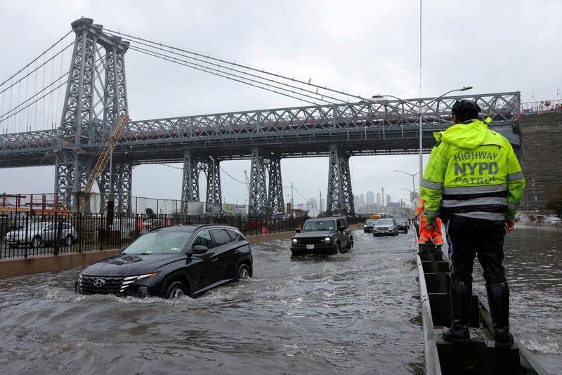 &copy; Reuters. FILE PHOTO: A police officer from the NYPD Highway Patrol looks on as motorists drive through a flooded street after heavy rains as the remnants of Tropical Storm Ophelia bring flooding across the mid-Atlantic and Northeast, at the FDR Drive in Manhattan 