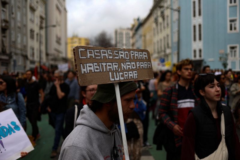 &copy; Reuters. FOTO DE ARQUIVO: Um homem carrega um cartaz enquanto pessoas se manifestam pelo direito à habitação acessível em Lisboa, Portugal, 1 de abril de 2023. REUTERS/Pedro Nunes/Foto de arquivo