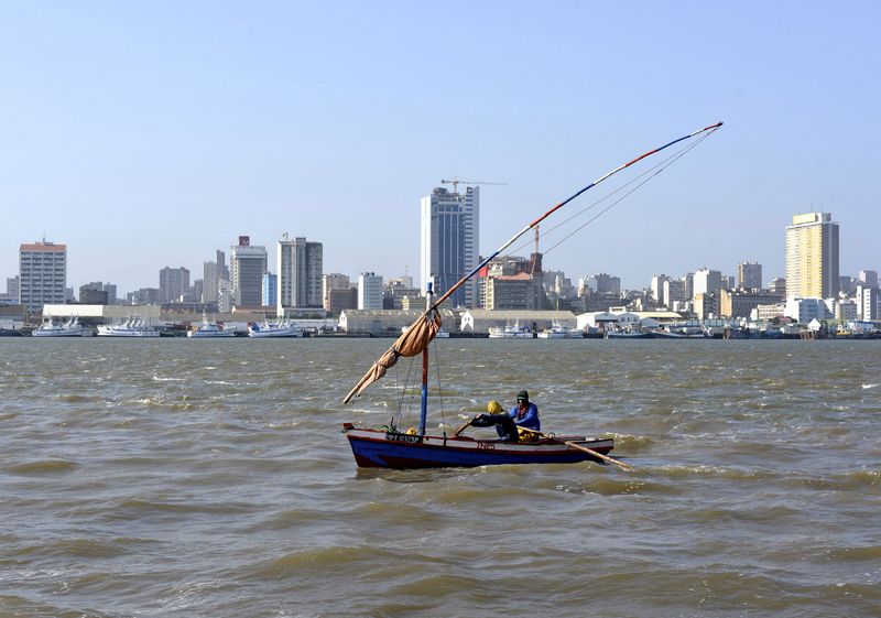© Reuters. FILE PHOTO: Traditional fishing boats sail as Mozambique's tuna fleet sits in dock beneath Maputo's skyline, in this picture taken August 15, 2015. Picture taken August 15, 2015.  REUTERS/Grant Lee Neuenburg/File Photo