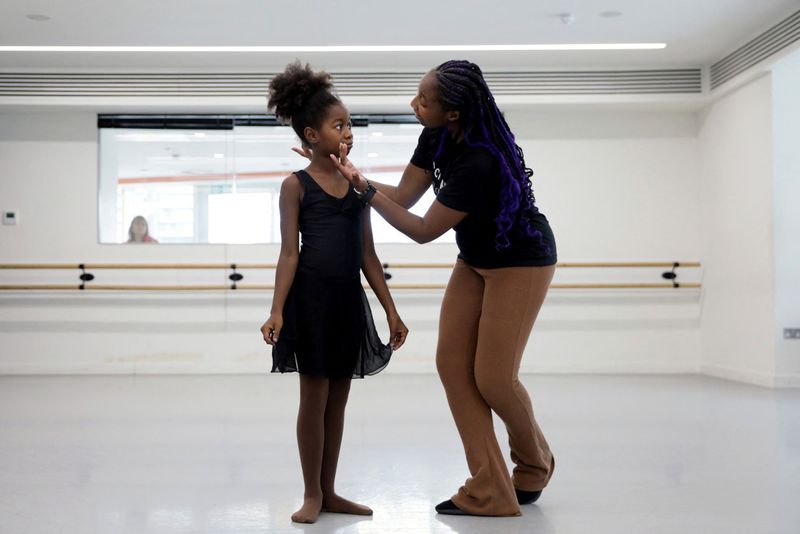 &copy; Reuters. Ruth Essel, 30, founder of Pointe Black Ballet School, and Kioni, 10, rehearse during class whilst an onlooker watches through the window in London, Britain, August 4, 2023. It was a pointed comment about her Afro-braided hair that spurred Essel to carv