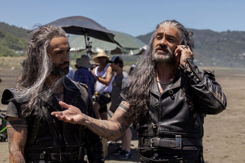 © Reuters. Taika Waititi talks on a phone as he stands next to Jade Daniels, his stunt double in the HBO romantic comedy series 