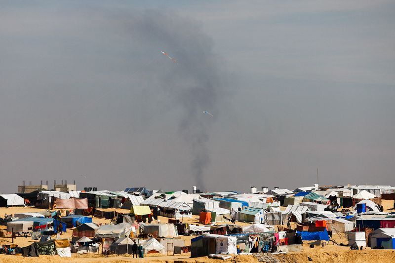 &copy; Reuters. Il fumo durante gli attacchi israeliani mentre i bambini palestinesi fanno volare gli aquiloni in una tendopoli a Rafah, nel sud della Striscia di Gaza, 8 febbraio 2024.  REUTERS/Ibraheem Abu Mustafa